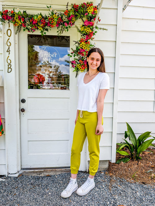 Alyssa standing outside of store with Keziah Lime Joggers, ankle length, and Self-Contrast Frankie White V-Neck tee.